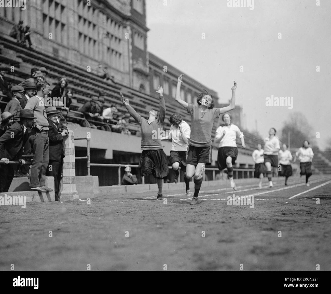 Le ragazze che finiscono una staffetta in una pista scolastica incontrano CA. 1925 Foto Stock