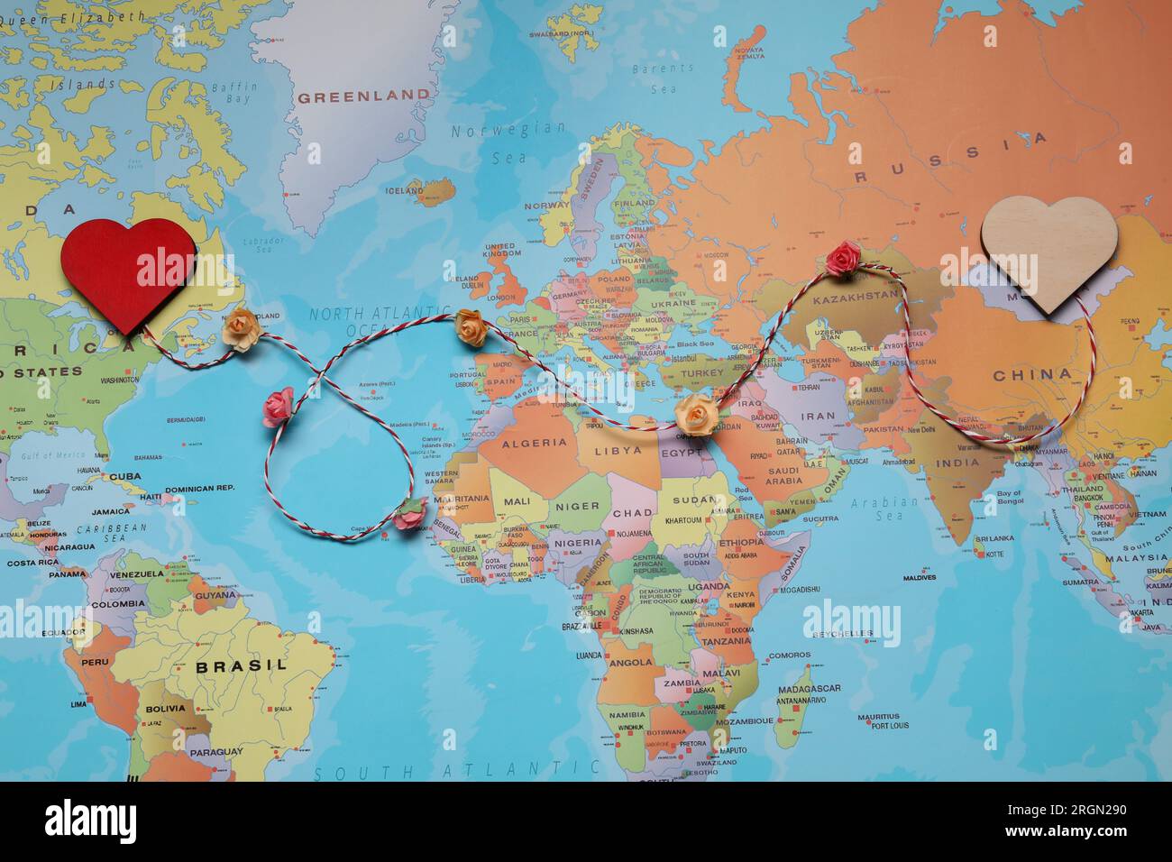 Cordoncino decorativo con cuori sulla mappa mondiale che simboleggia la connessione nelle relazioni a lunga distanza, vista dall'alto Foto Stock