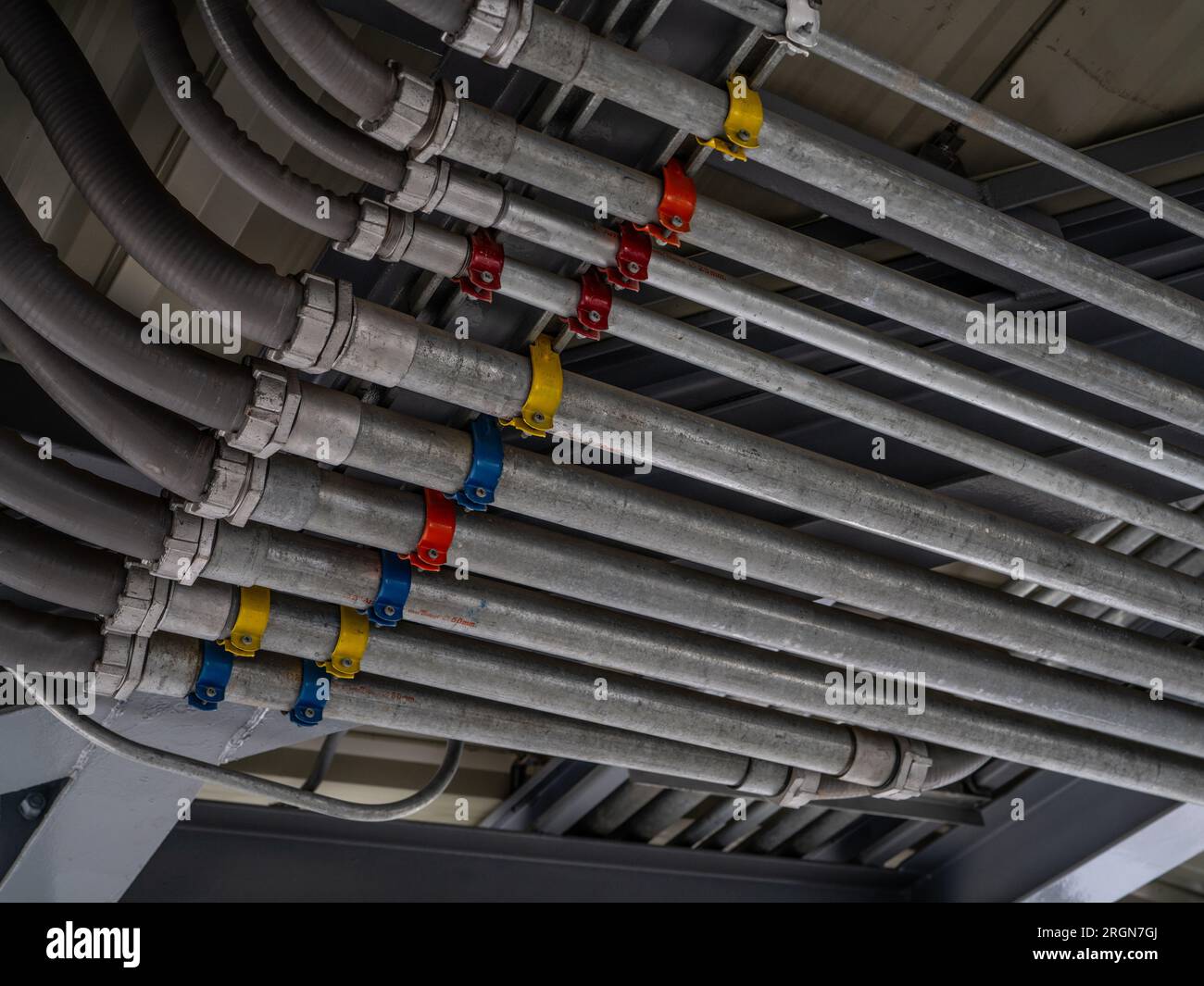 Sistema di condotti elettrici e tubo di cavo elettrico installati sul soffitto dell'edificio. Infrastrutture industriali. Installazione efficiente del cablaggio elettrico Foto Stock