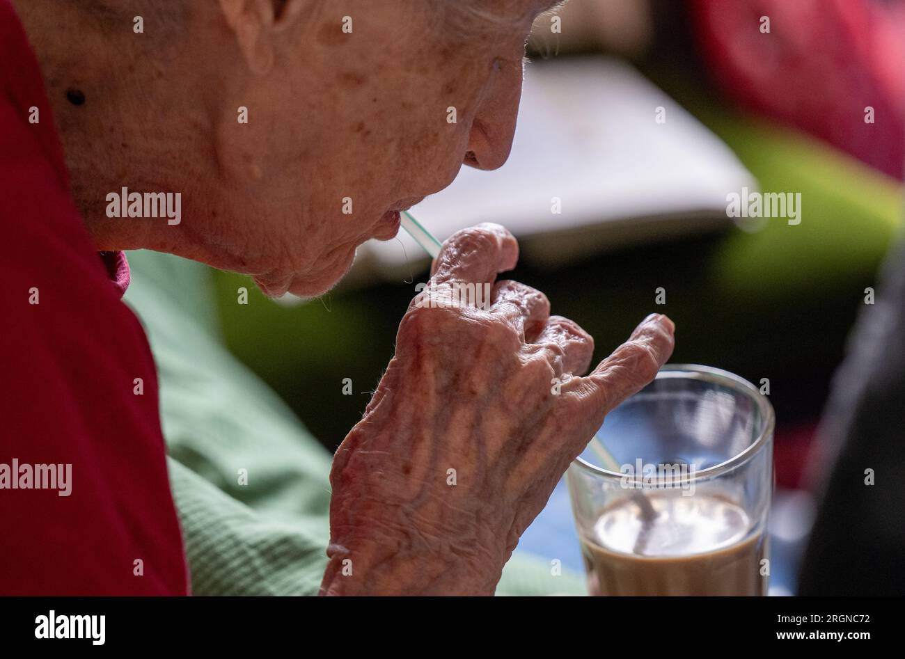 Berlino, Germania. 31 luglio 2023. Brigitte Richter, una cittadina anziana di 97 anni che ha bisogno di cure, beve caffè da un bicchiere portato in camera da un'infermiera con l'aiuto di una paglia. Crediti: Monika Skolimowska/dpa/Alamy Live News Foto Stock