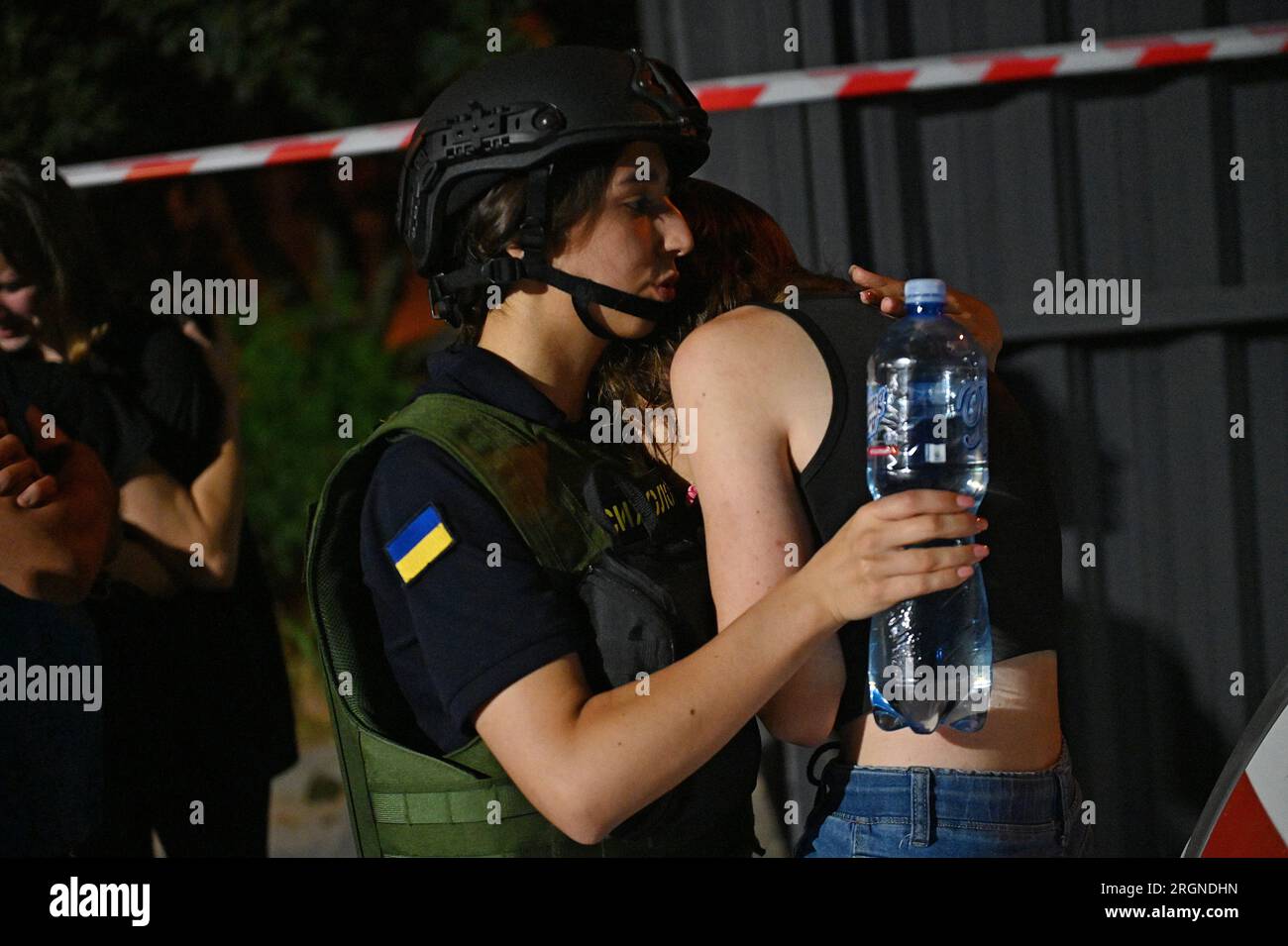 Non esclusiva: ZAPORIZHZHIA, UCRAINA - 9 AGOSTO 2023 - Un ufficiale di polizia conforta una donna dopo un attacco missilistico russo avvenuto mercoledì sera Foto Stock