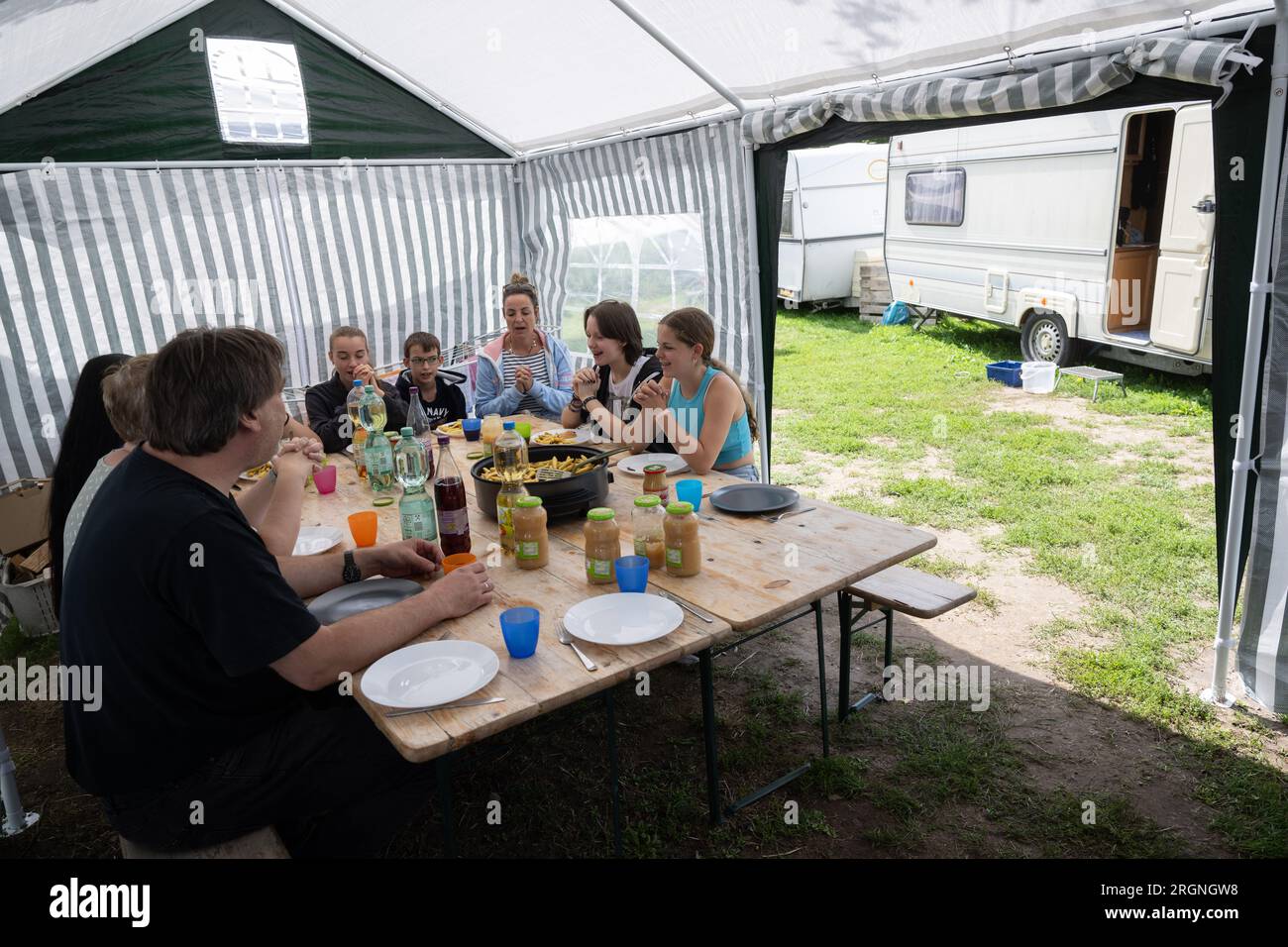 St Leon Rot, Germania. 8 agosto 2023. I membri del personale della chiesa del campeggio pregano in una tenda, che si trova su un terreno del campeggio a Lake St Leon, prima di mangiare. La Chiesa protestante di Baden-Württemberg organizza dodici chiese da campeggio nello stato. Approfittano del tempo libero delle persone in vacanza per risvegliare il loro interesse per la fede e avviare una conversazione con loro al riguardo. Crediti: Marijan Murat/dpa/Alamy Live News Foto Stock