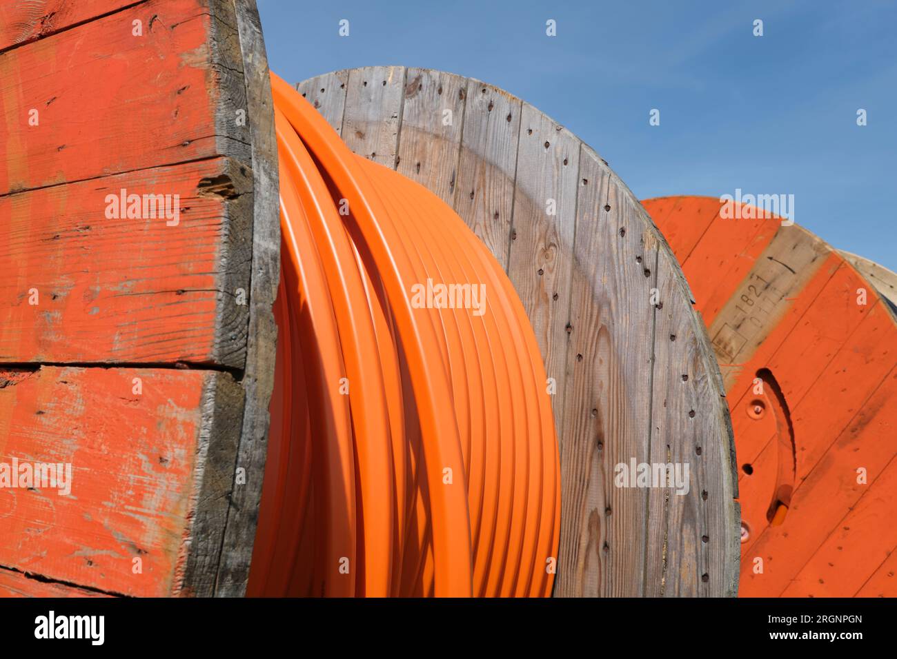 Rotoli di legno di cavo in tubo industriale di colore arancione per il cablaggio Internet in fibra ottica sotterranea. Foto Stock