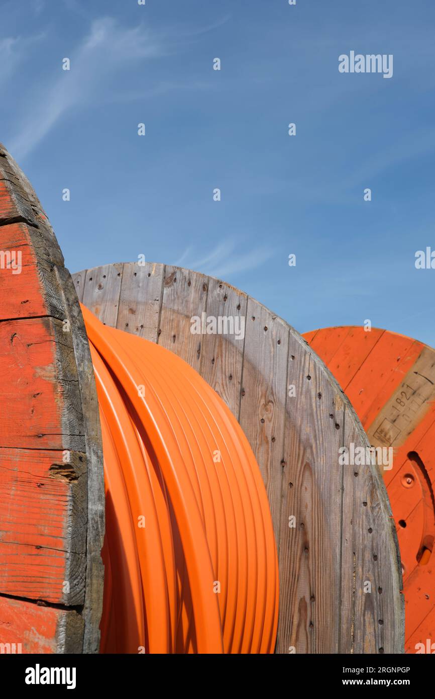 Rotoli di legno di cavo in tubo industriale di colore arancione per il cablaggio Internet in fibra ottica sotterranea. Foto Stock
