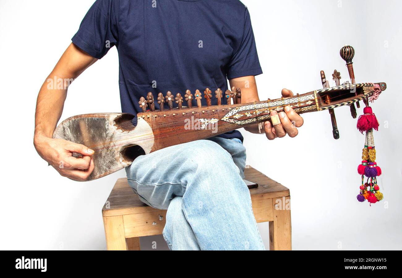Uomo che suona Rubab uno strumento a corde del popolo orientale del Pakistan settentrionale isolato su sfondo bianco. Foto Stock