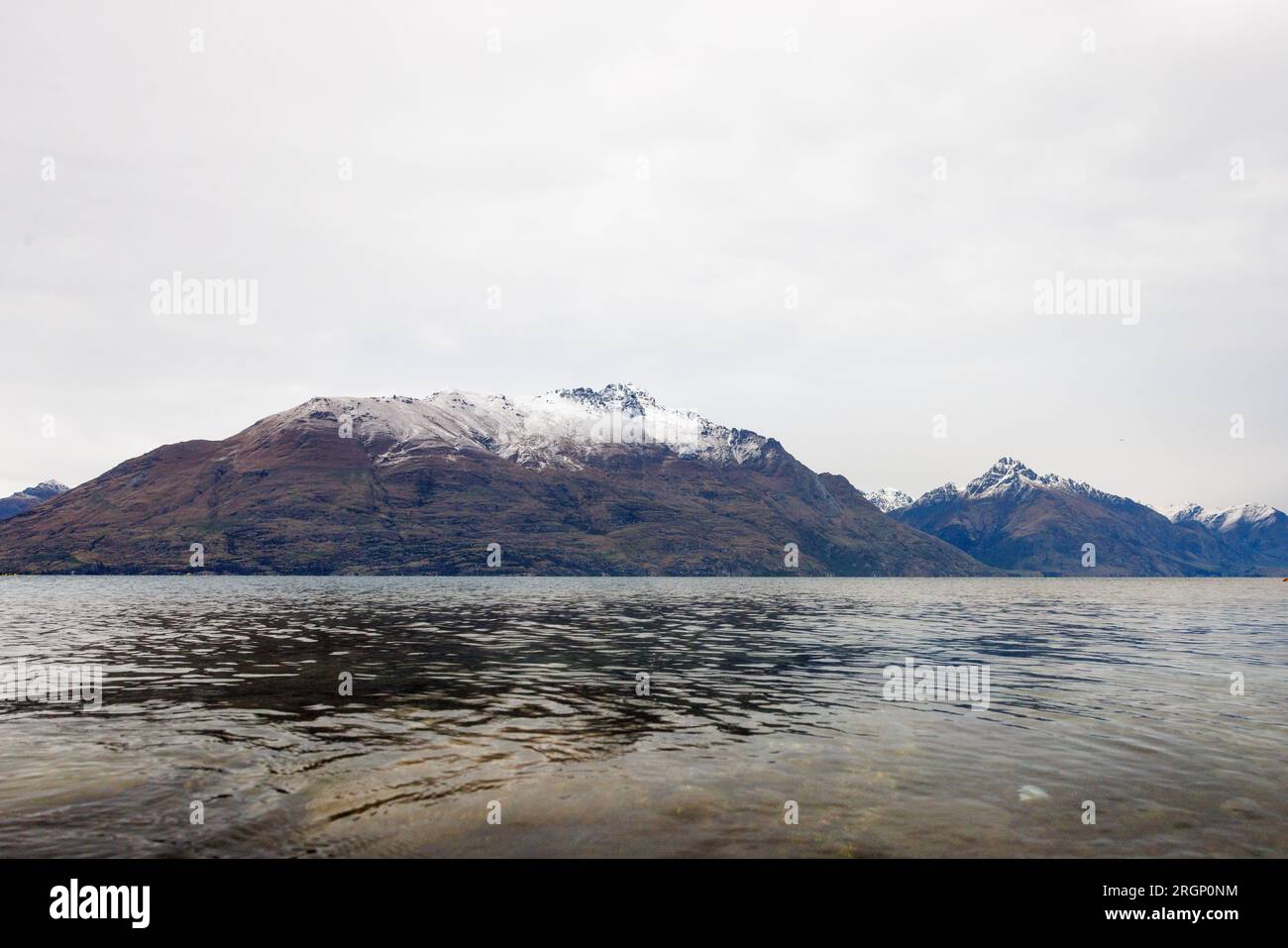 Una serie di picchi trovati a Queenstown in nuova Zelanda. L'immagine mostra un lago in primo piano e le montagne con neve sulle cime più alte sullo sfondo Foto Stock