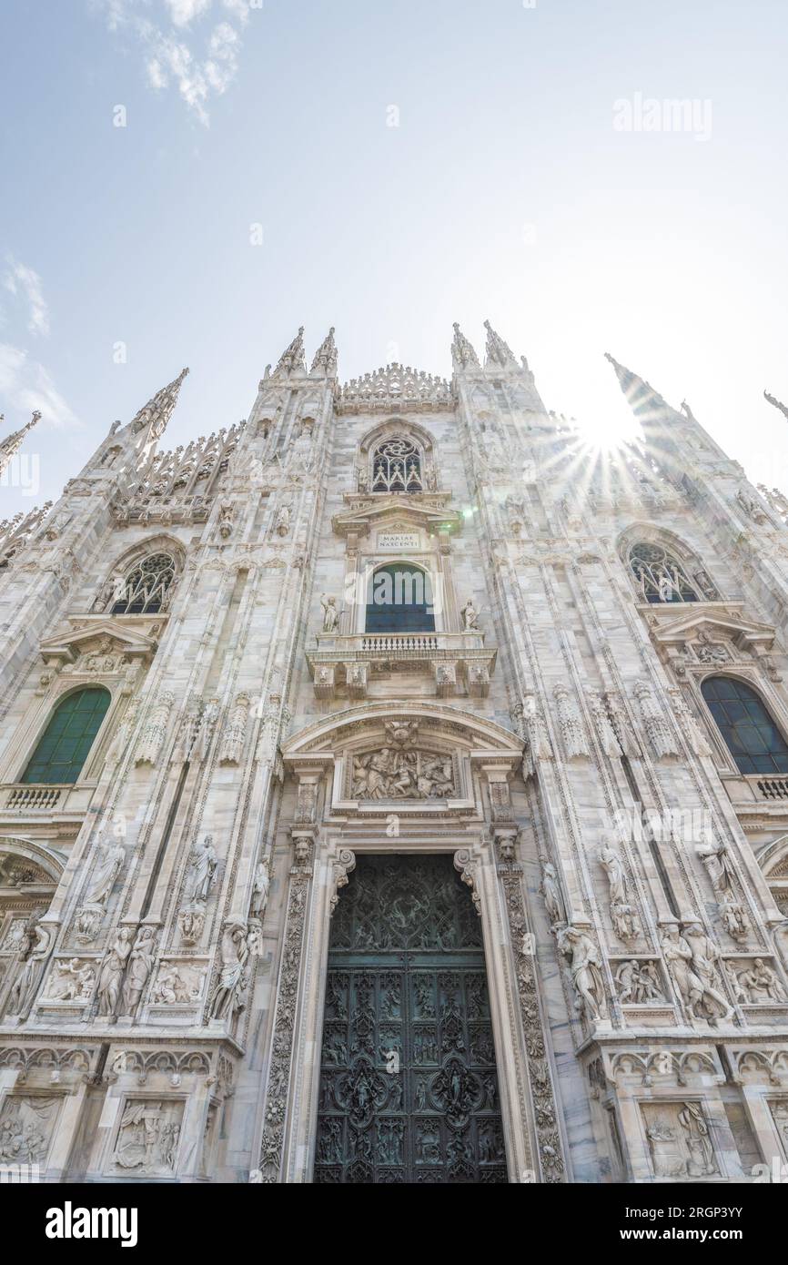 Cattedrale di Milano, in italiano: Duomo di Milano o Cattedrale metropolitana-Basilica della Natività di Santa Maria. Vista della porta principale e della facciata in marmo bianco nelle soleggiate giornate estive. Milano, Lombardia, Italia Foto Stock