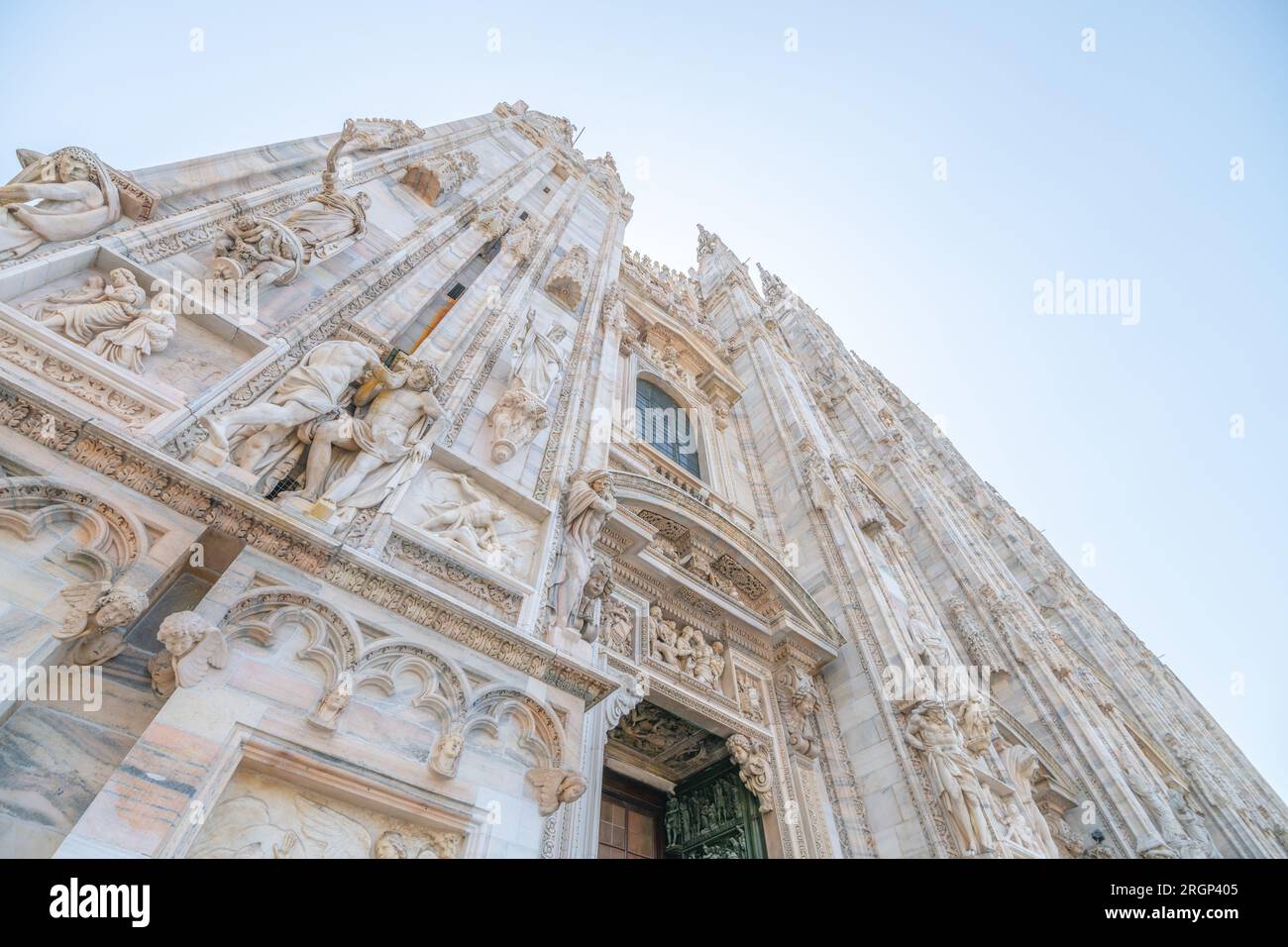 Cattedrale di Milano, in italiano: Duomo di Milano o Cattedrale metropolitana-Basilica della Natività di Santa Maria. Vista della porta principale e della facciata in marmo bianco nelle soleggiate giornate estive. Milano, Lombardia, Italia Foto Stock