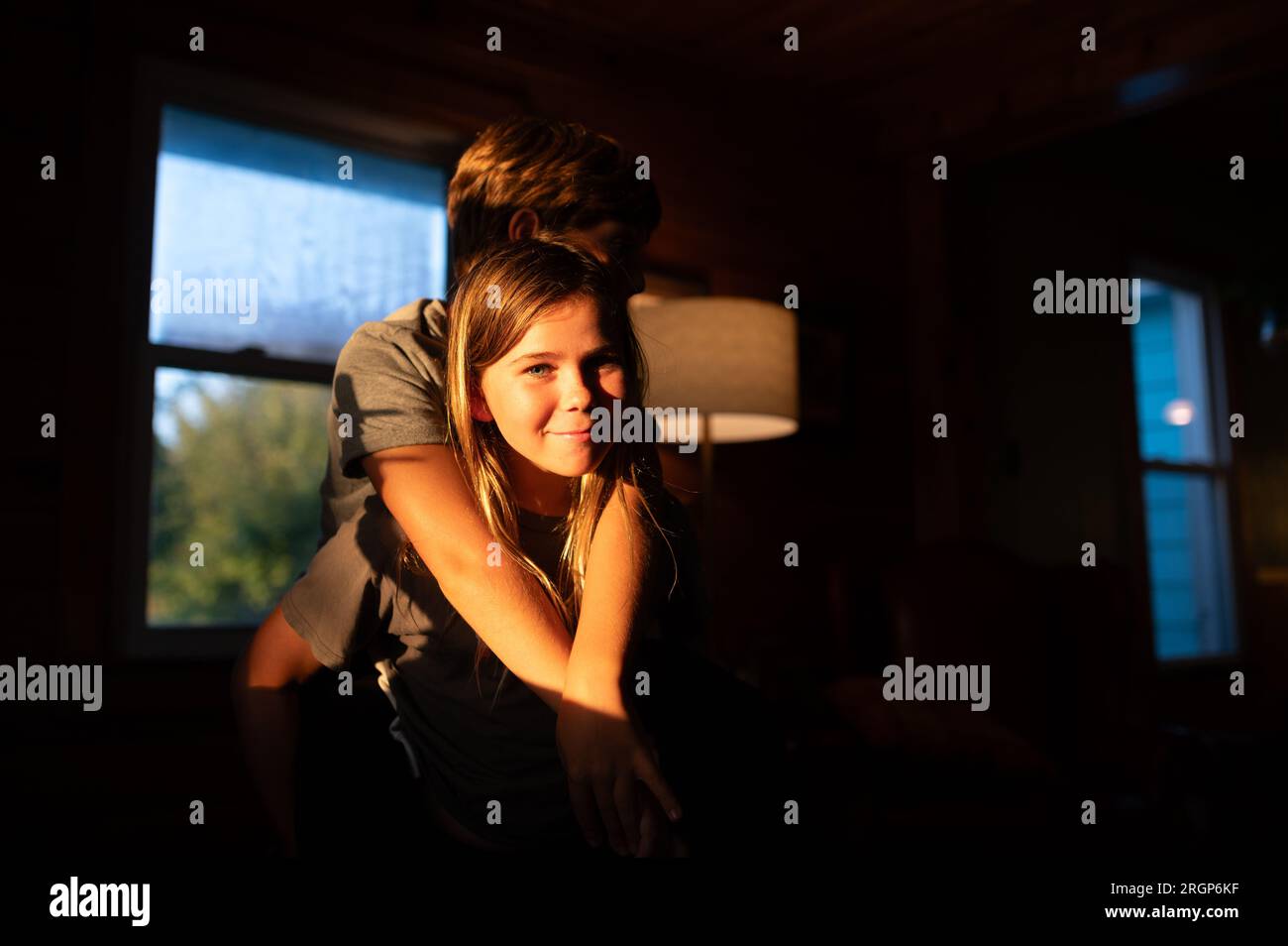 Ritratto di un ragazzo che guarda la macchina fotografica con il fratello all'interno al tramonto Foto Stock