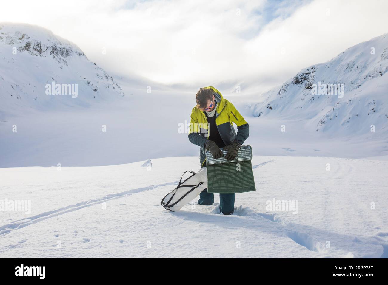 L'alpinista si arrotola su una zona notte, dietro le montagne innevate. Foto Stock