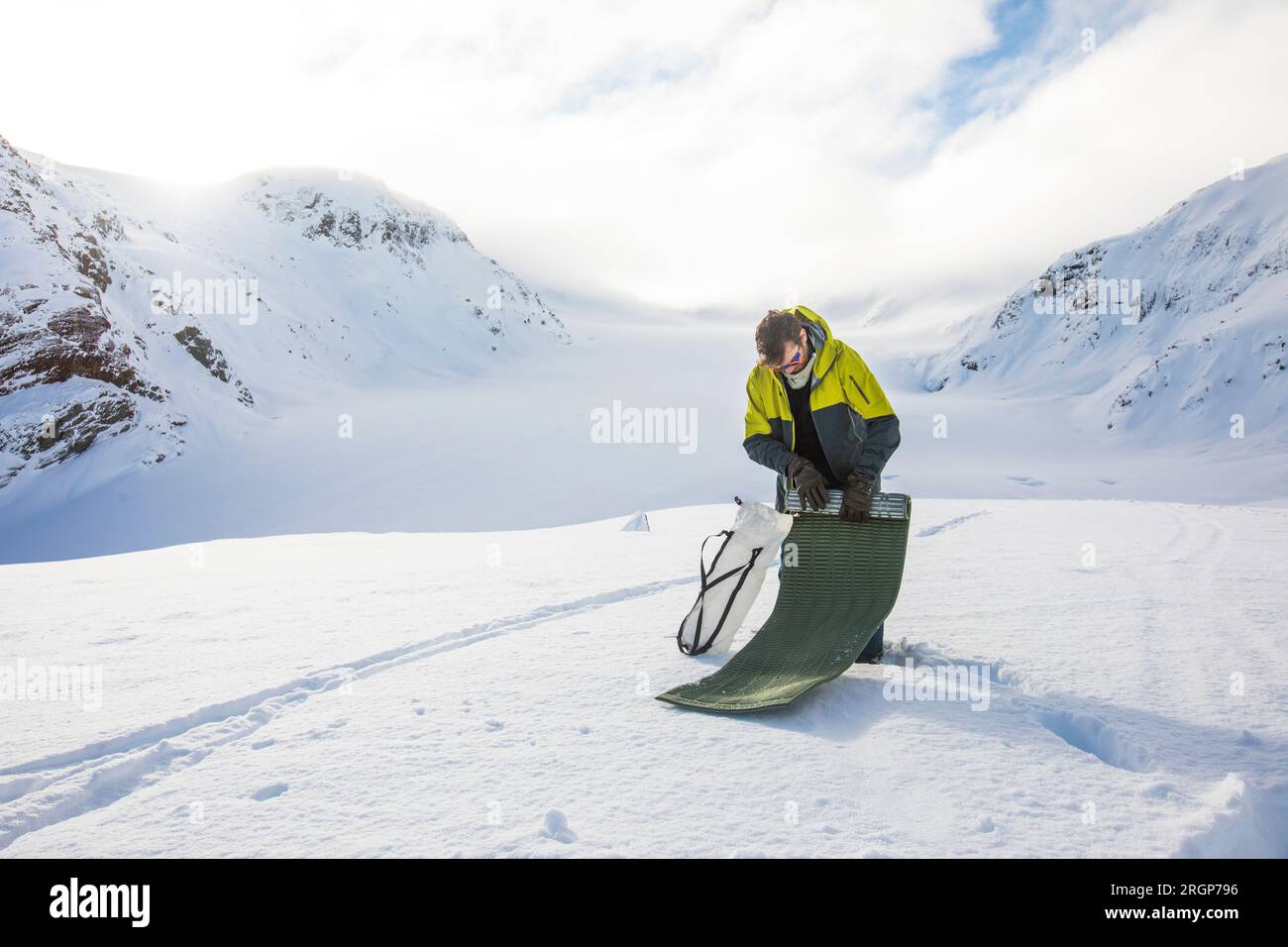 Dopo il campeggio sul ghiacciaio, l'uomo arrotola il tappetino per dormire. Foto Stock