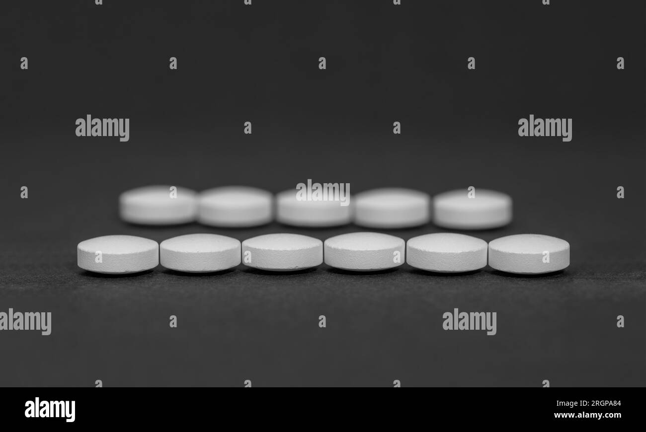 Pillole ordinate in modo ordinato, droghe su sfondo nero Foto Stock