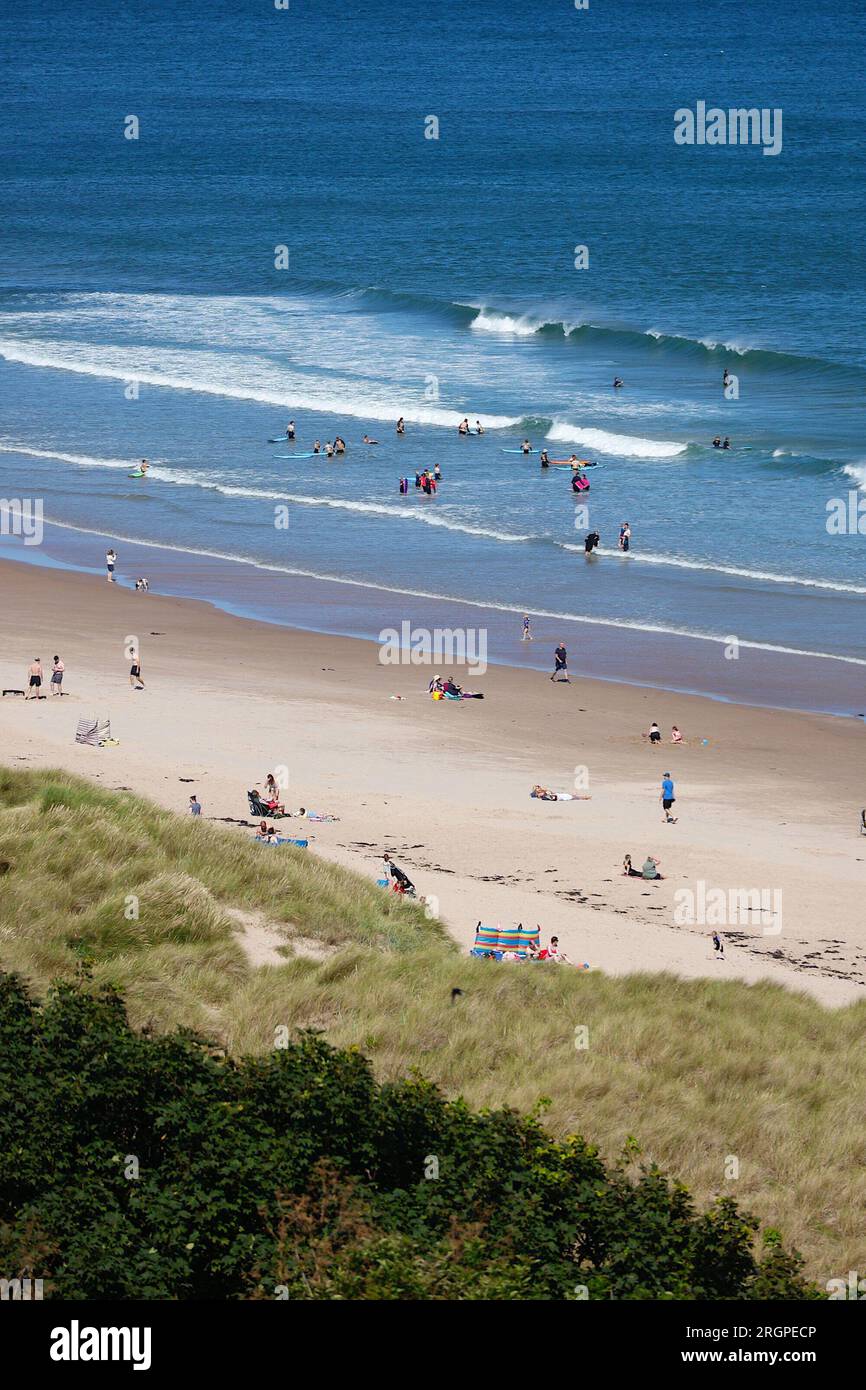 Bamburgh, Northumberland, Regno Unito. 11 agosto 2023. Tempo nel Regno Unito: Una giornata luminosa e soleggiata sulla spiaggia di Bamburgh, mentre i visitatori e i surfisti si godono il sole. Credito fotografico: PAL News/Alamy Live News Foto Stock