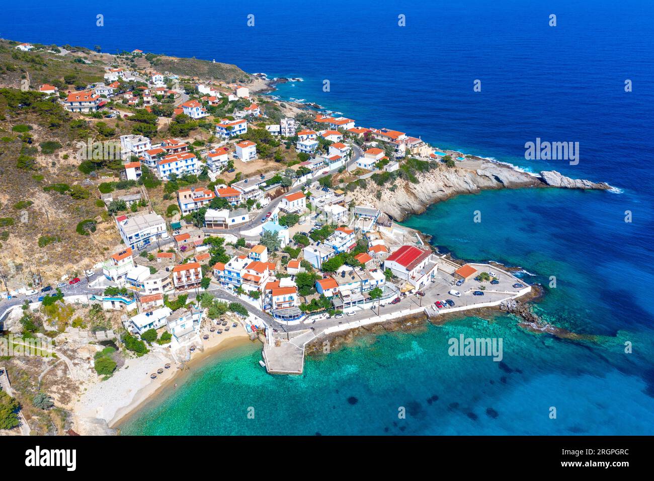 Un incantevole villaggio greco di pescatori di Armenistis in una tranquilla mattinata d'estate. Porto con spiaggia locale in acque cristalline a Ikaria, Grecia Foto Stock