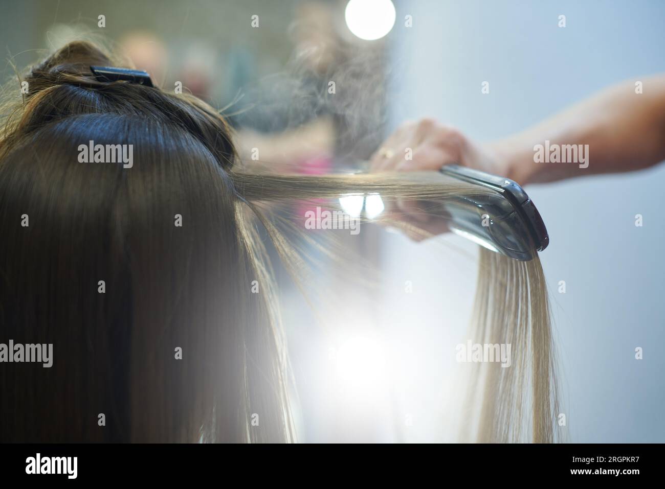 Lisciare i capelli con cheratina e un ferro da stiro Foto Stock