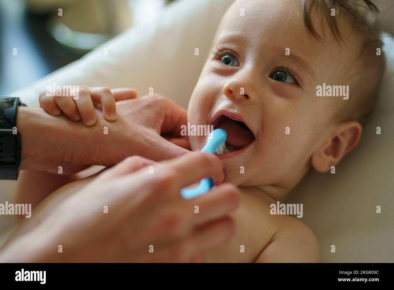 Mamma usa uno spazzolino per spazzolare i denti del suo bambino Foto Stock