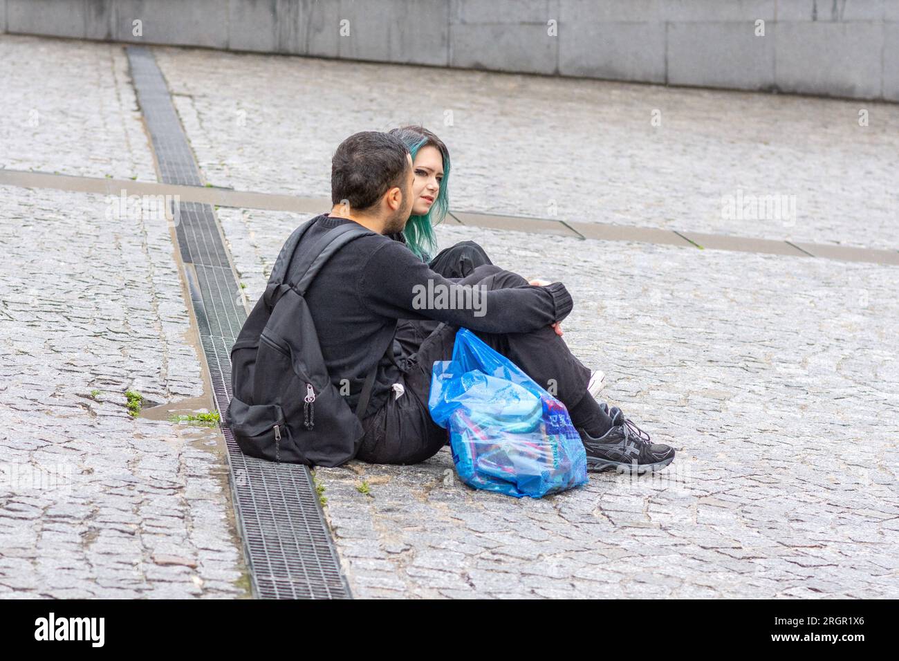Una giovane coppia sedeva su una piazza acciottolata a parlare insieme a Parigi, Francia. Foto Stock