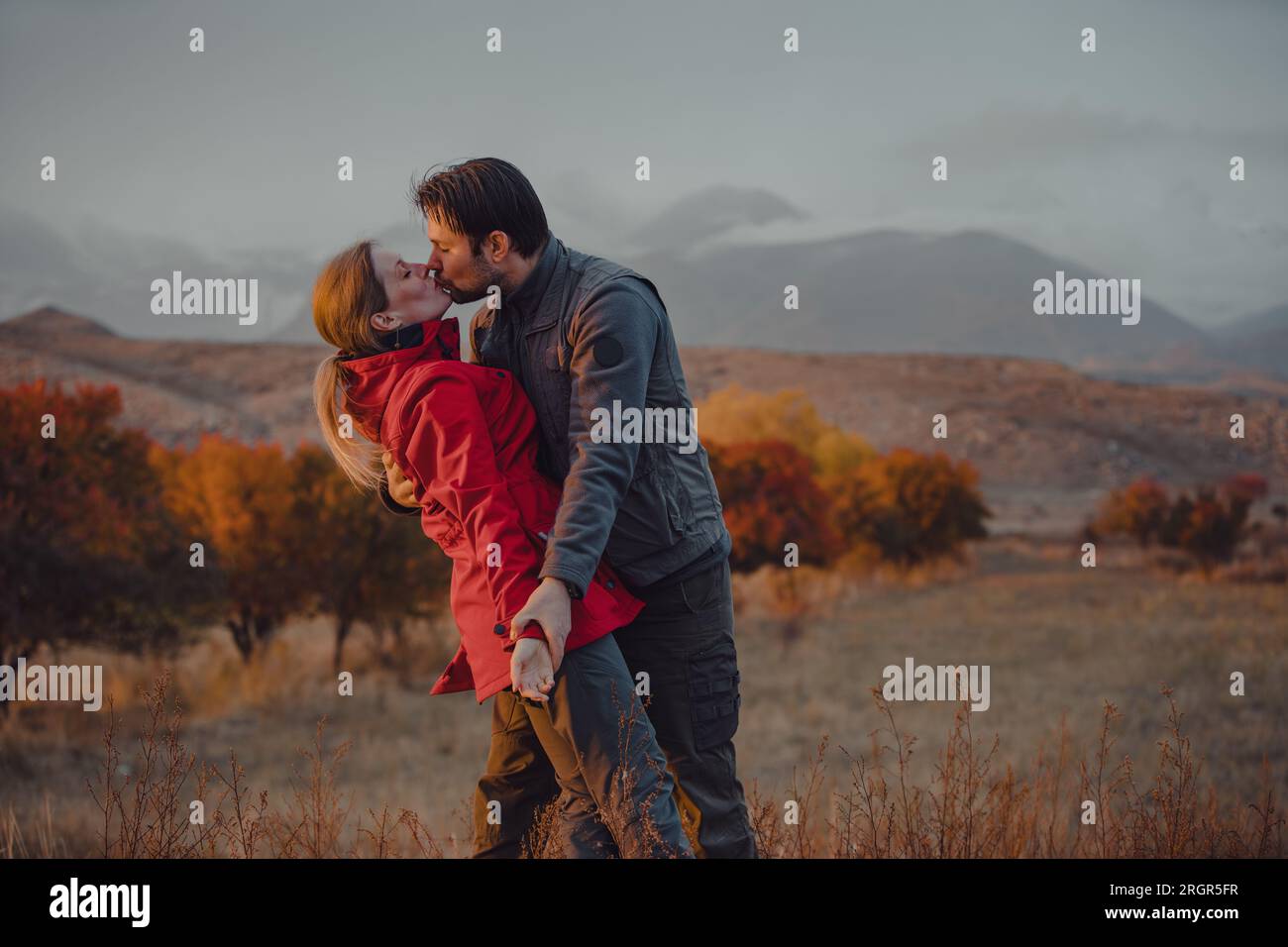 Felice giovane coppia che si bacia sulle montagne in autunno Foto Stock