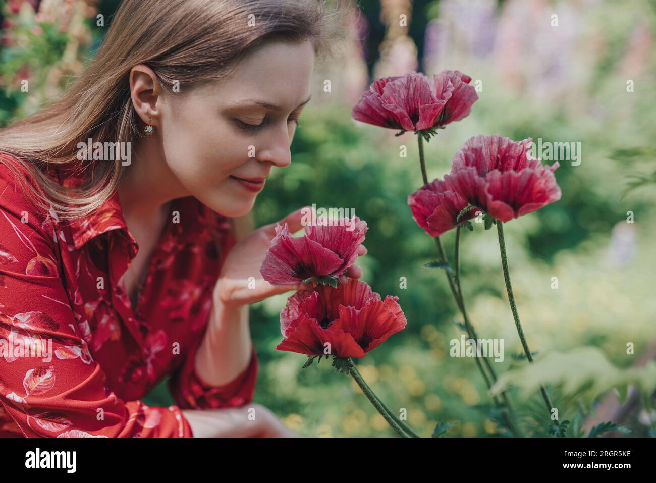Ritratto di giovane bella donna con papaveri in giardino Foto Stock