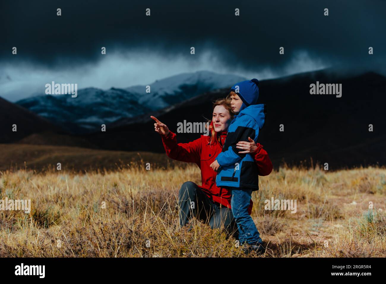 Madre e figlio che guardano sulle montagne con il tempo buio e tempestoso Foto Stock