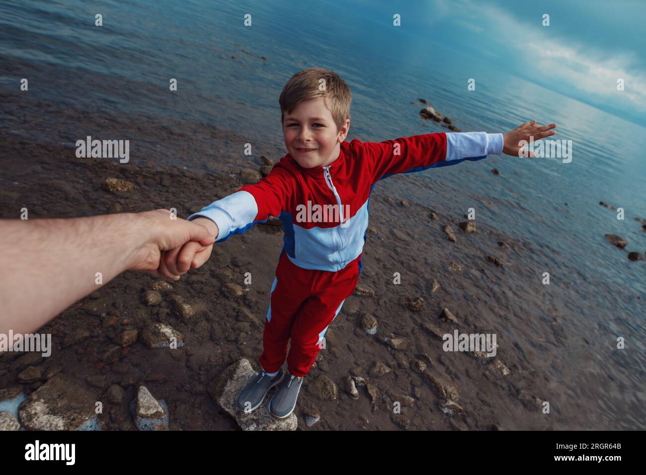 Il padre estende la mano a suo figlio in piedi su una pietra nell'acqua Foto Stock