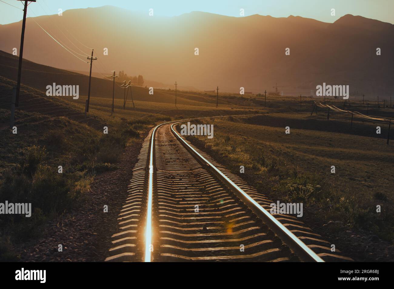 Ferrovia tra le montagne al caldo tramonto Foto Stock