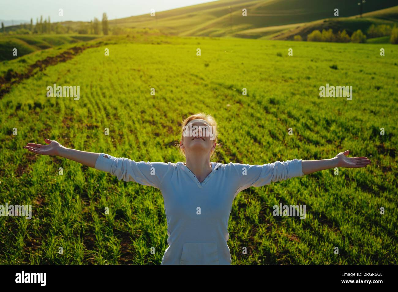 Giovane donna felice che delizia il bel tempo sul campo verde Foto Stock