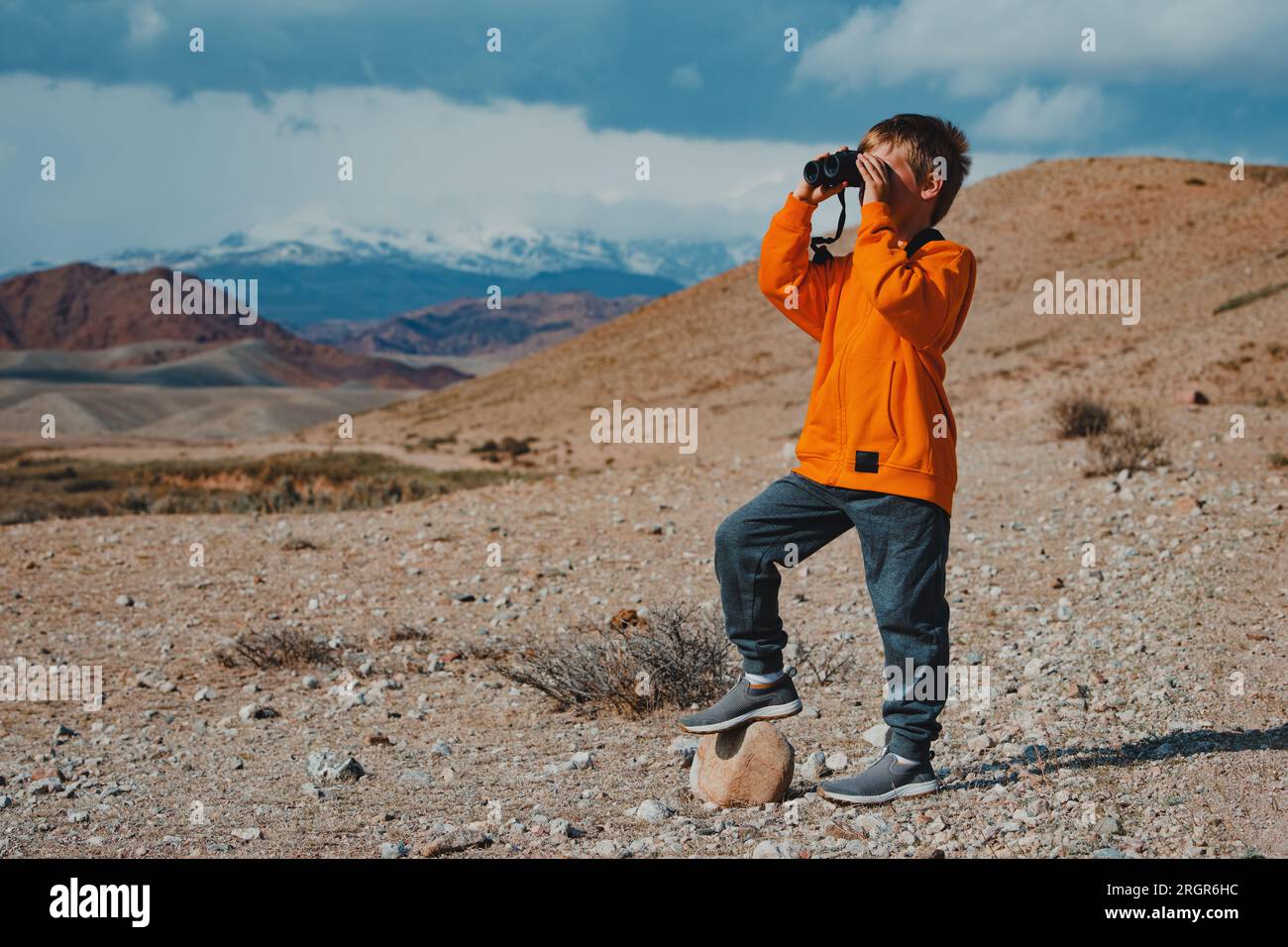 Ragazzo turista che cerca un binocolo in montagna Foto Stock