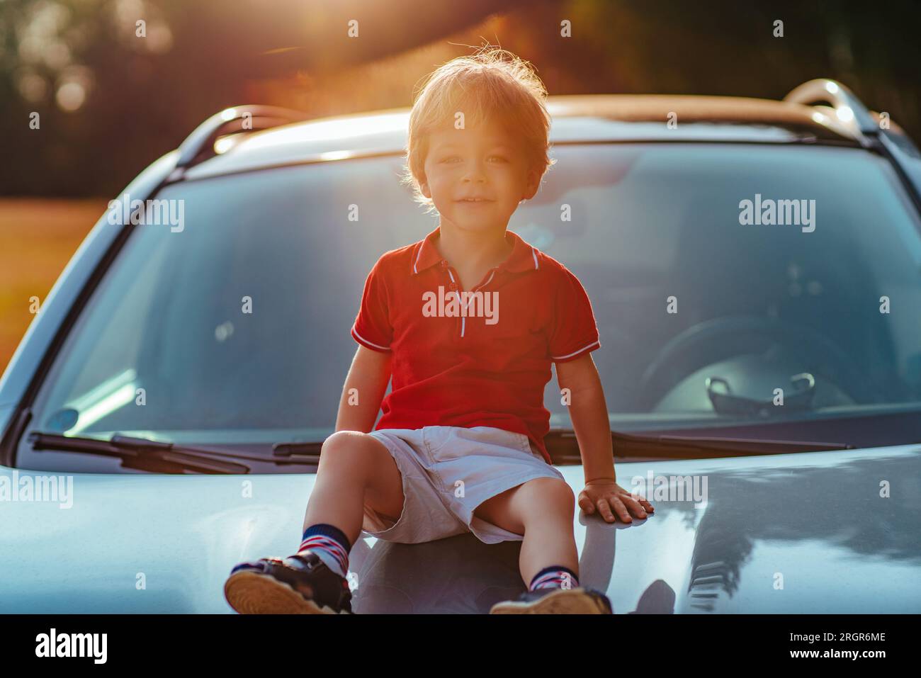 Bambino di due anni siede sul cofano dell'auto Foto Stock
