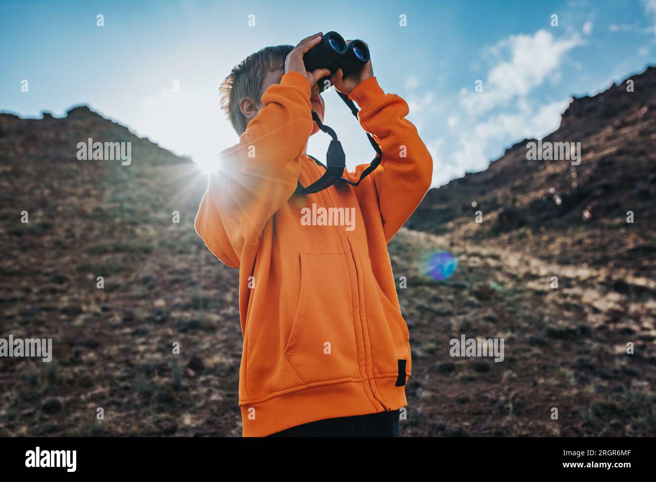 Ritratto di un ragazzo turista che guarda in binocolo in montagna Foto Stock