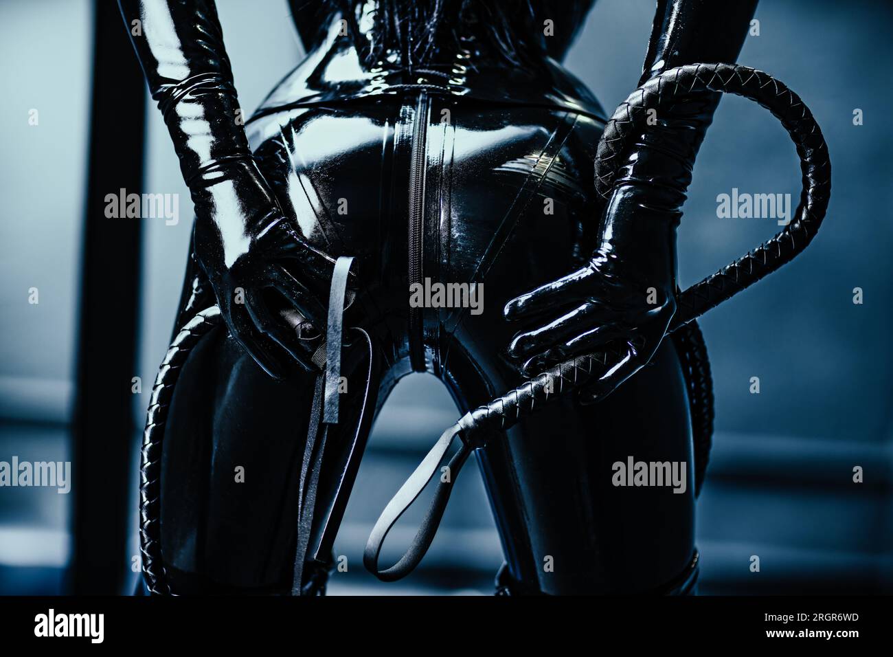 Donna BDSM in lattice nero con frusta Foto Stock