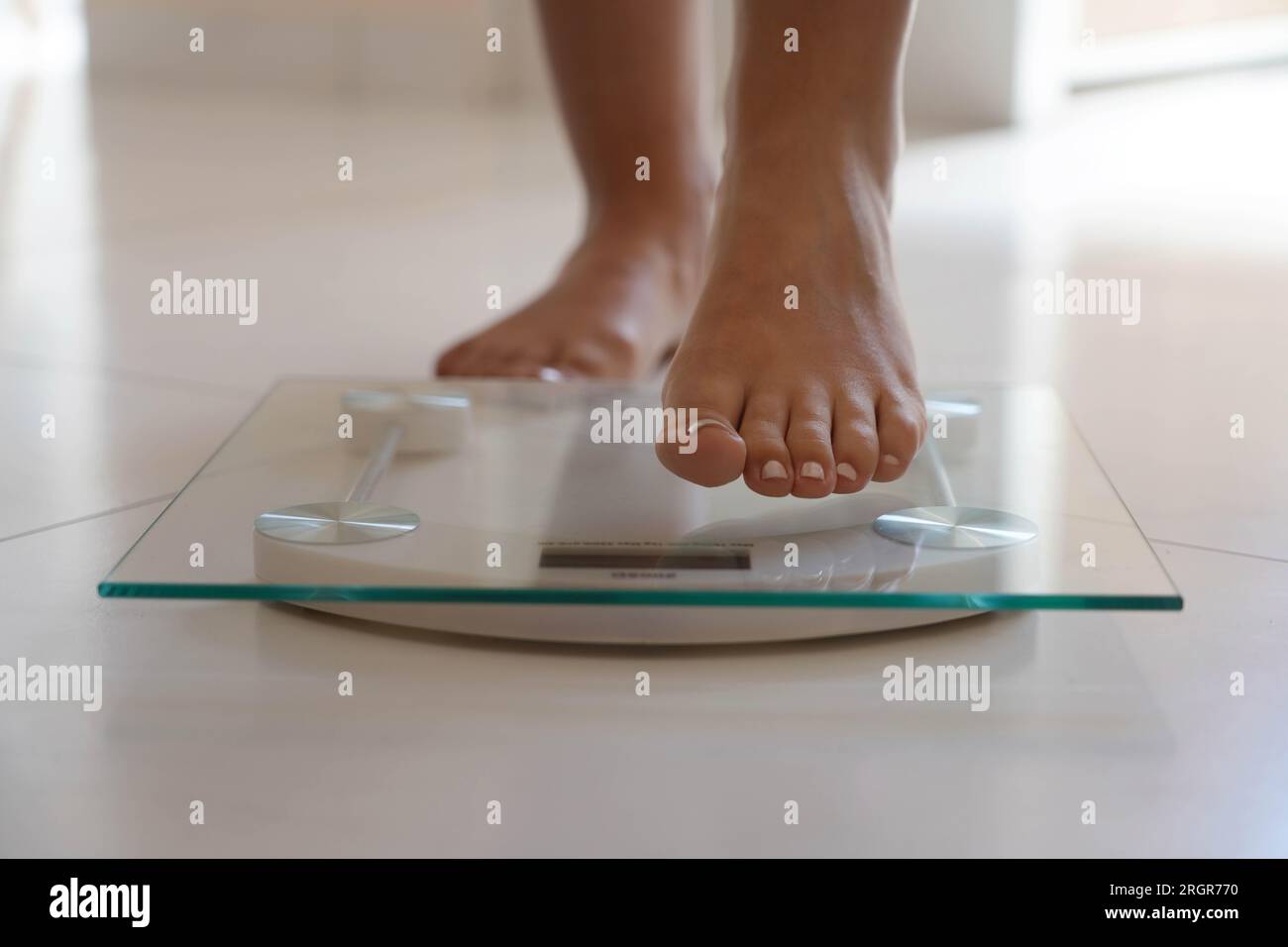 Primo piano del piede femmina che cala sulla bilancia. Stile di vita sano, dieta e concetto di sport. Foto Stock