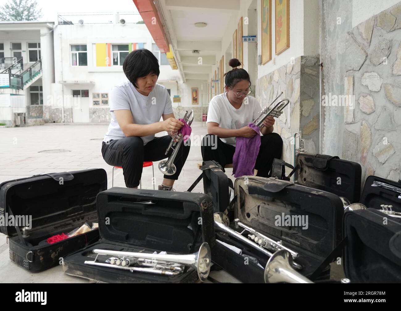 Laishui, provincia cinese di Hebei. 11 agosto 2023. Gli insegnanti puliscono gli strumenti musicali in una scuola nel villaggio di Longmen nella contea di Laishui, nella provincia di Hebei nella Cina settentrionale, 11 agosto 2023. Alcune scuole, situate nelle zone montagnose della contea di Laishui, hanno recentemente svolto lavori di recupero post-alluvione. Il personale competente ha studiato accuratamente le scuole per potenziali rischi per la sicurezza, pulito i campus e ha effettuato la disinfezione per la prevenzione e il controllo delle epidemie. Crediti: Yang Shiyao/Xinhua/Alamy Live News Foto Stock