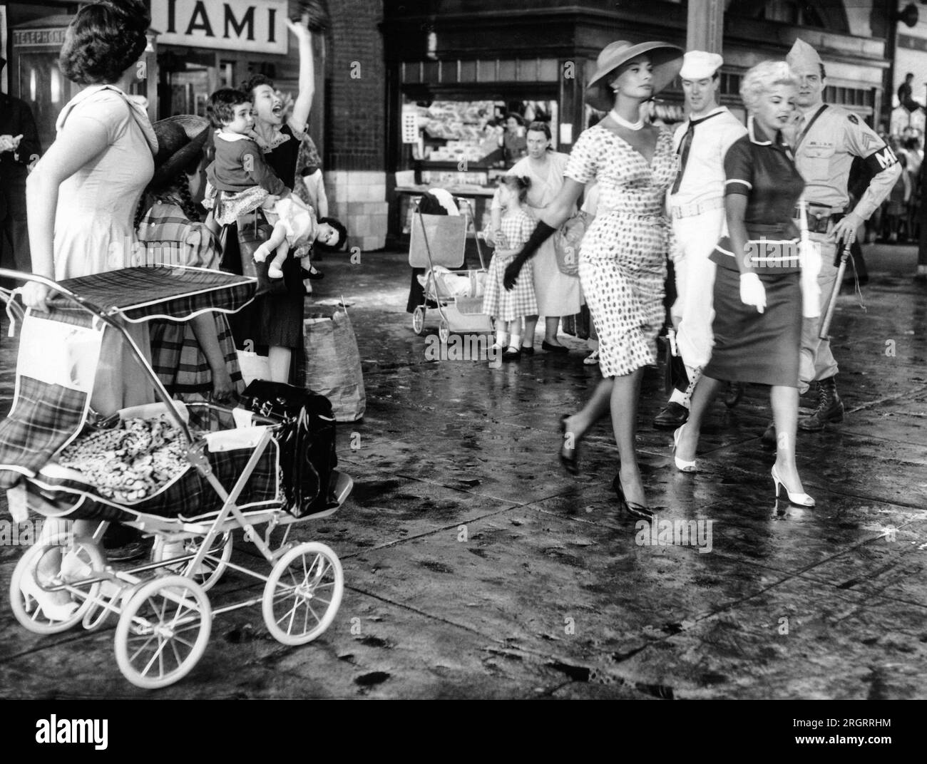 Long Beach, New York: 24 giugno 1958 Sophia Loren e Barbara Nichols attraggono gli occhi dei militari durante le riprese di "quel tipo di donna". Il cartello dice "Miami", ma in realtà è lo staion della ferrovia a Long Beach, Long Island. Foto Stock