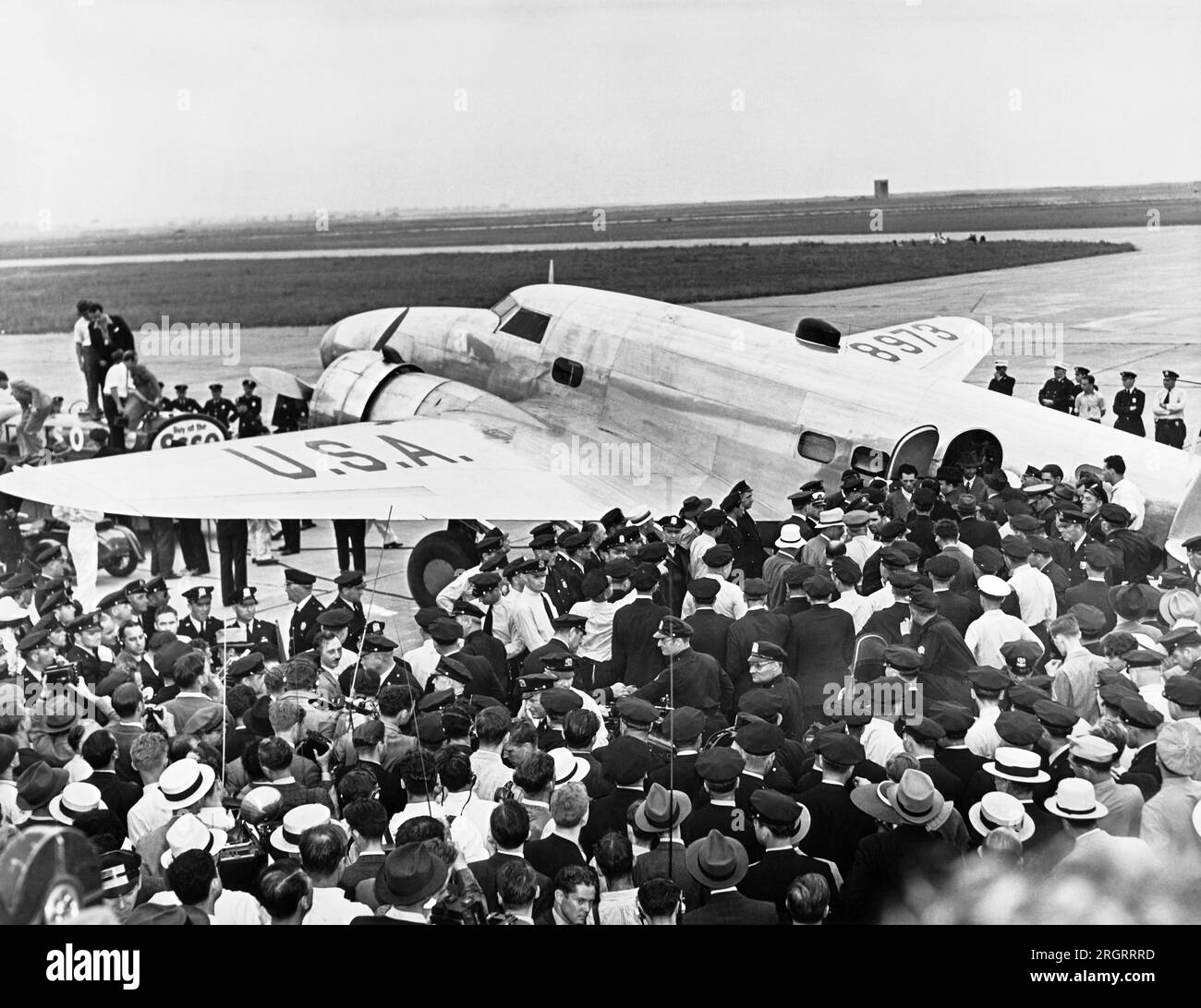New York, New York: 14 luglio 1938 la polizia circonda l'aereo Lockheed 14N Super Electra di Howard Hughes all'aeroporto Floyd Bennett di Brooklyn quando atterra lì dopo aver volato in tutto il mondo stabilendo un nuovo record di 3 giorni, 19 ore e 14 minuti, battendo il record di Wiley Posts. Faceva parte di una promozione per attirare le persone alla Fiera Mondiale di New York. Foto Stock