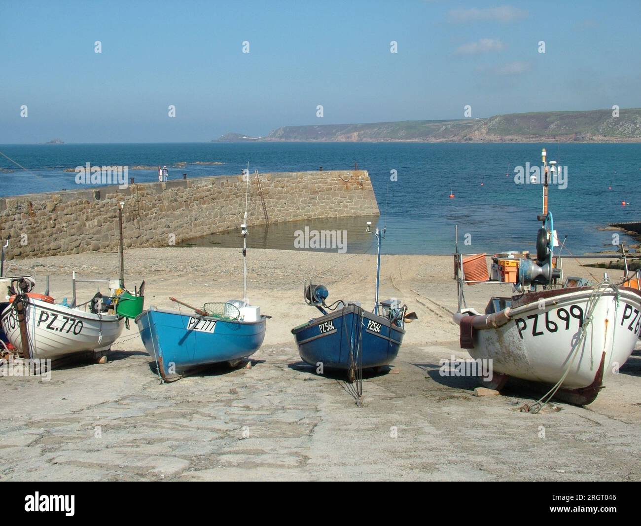 Piccole barche da pesca allineate sullo scalo nella baia di Sennan con il frangiflutti che ripara il piccolo porto dall'oceano Atlantico su un luminoso Foto Stock