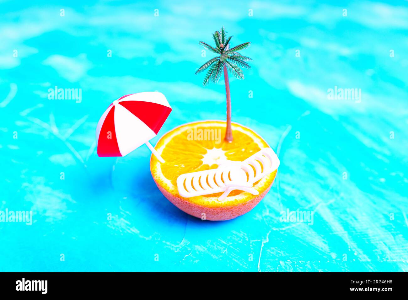 Atmosfere esotiche per le vacanze: Una sdraio giocattolo, una palma e una fetta di agrumi si uniscono per creare un'affascinante composizione isolana. Foto Stock