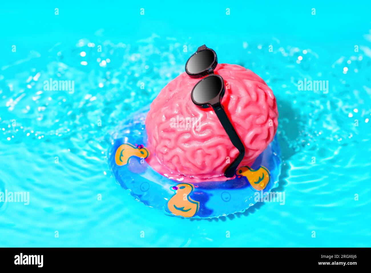 Il simpatico personaggio del modello di cervello umano che indossa occhiali da sole neri galleggia su un tubo gonfiabile in piscina in una soleggiata giornata estiva. Concep. Mod. Rilassamento cervello Foto Stock