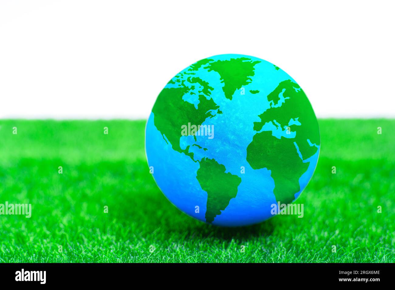 Globo in miniatura su un prato verde verdeggiante. Eco-coscienza, sviluppo sostenibile e promozione di una responsabilità condivisa per il bene della Terra Foto Stock