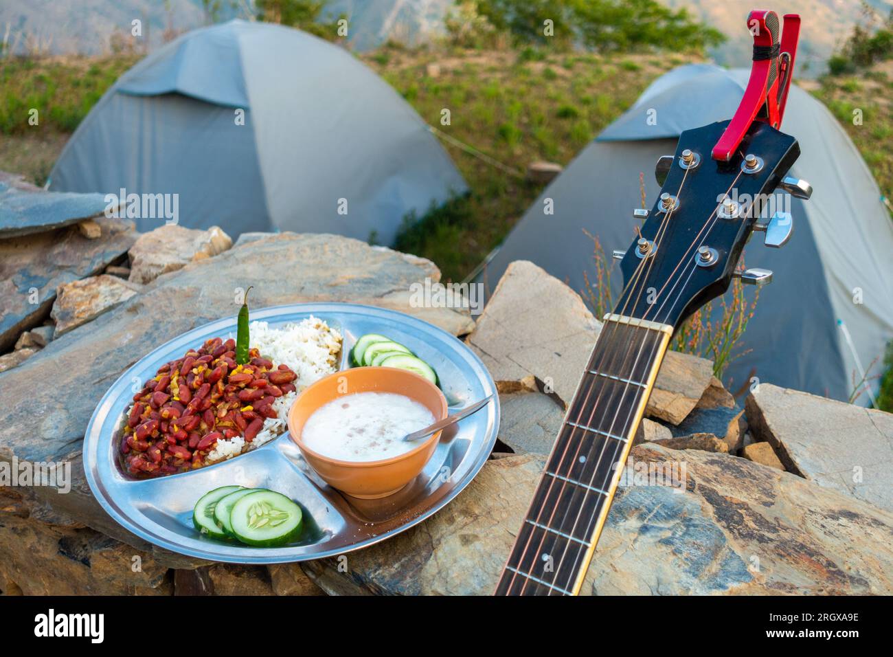 Atmosfera da campeggio Uttarakhand: Festa rajma-chawal con cagliata e insalata, fissata contro tende e strumenti di chitarra. Autentici sapori dell'India del Nord in mezzo alla natura Foto Stock