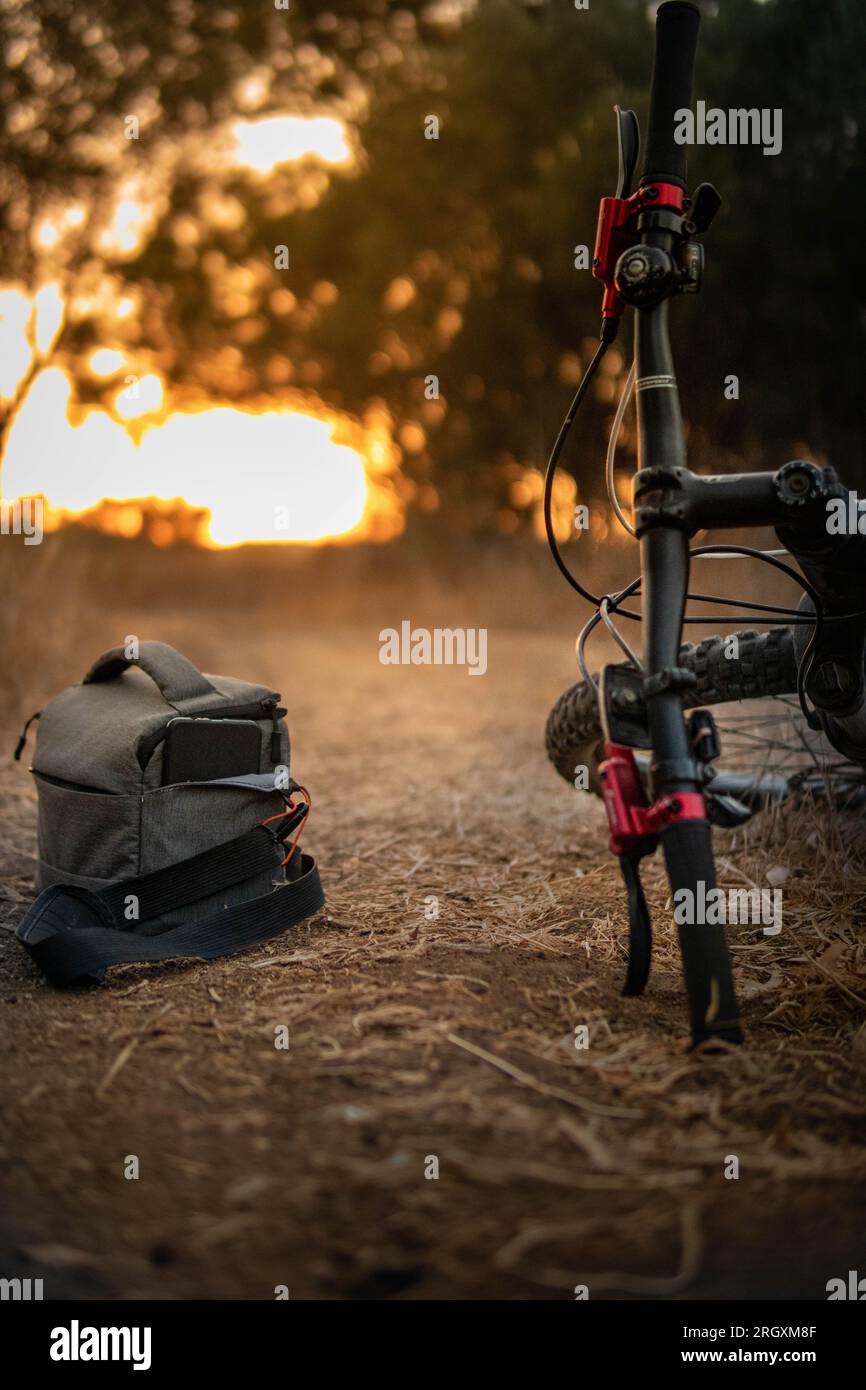 Kameratasche neben einem Fahrrad im Sonnenuntergang Foto Stock