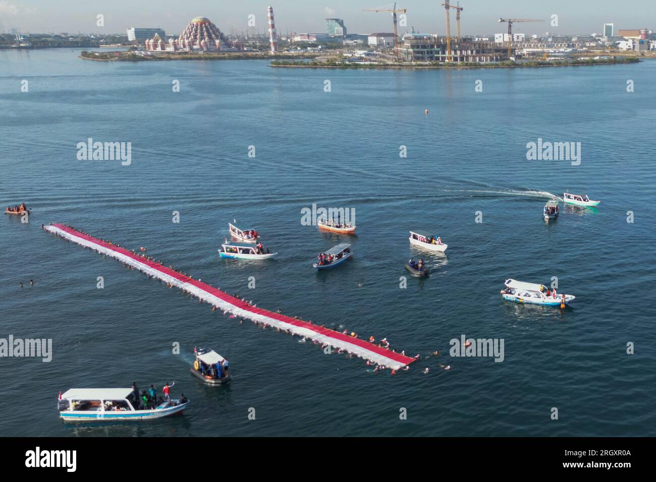 Makassar, Sulawesi meridionale, Indonesia. 12 agosto 2023. Foto aerea di un certo numero di nuotatori che sventolano e sfilano la bandiera della Repubblica di Indonesia nello stretto di Makassar, Sulawesi meridionale Indonesia, sabato 12 agosto 2023. Allo scoppio della bandiera della Repubblica di Indonesia, alta 78 metri, hanno partecipato 140 nuotatori e hanno sfilato per 1,8 chilometri nuotando. (Immagine di credito: © Moh Niaz Sharief/ZUMA Press Wire) SOLO USO EDITORIALE! Non per USO commerciale! Foto Stock