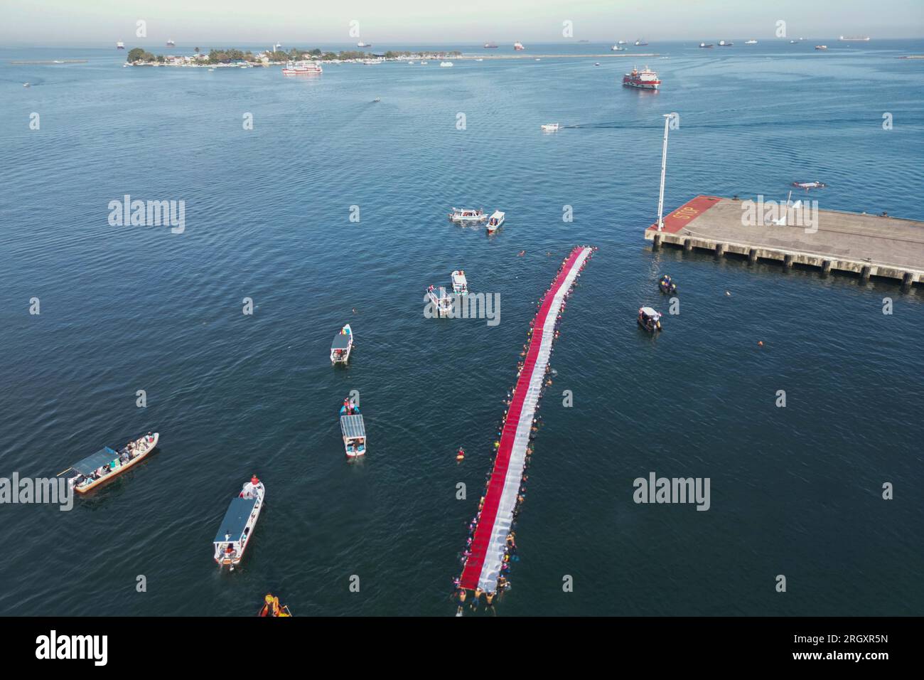 Makassar, Sulawesi meridionale, Indonesia. 12 agosto 2023. Foto aerea di un certo numero di nuotatori che sventolano e sfilano la bandiera della Repubblica di Indonesia nello stretto di Makassar, Sulawesi meridionale Indonesia, sabato 12 agosto 2023. Allo scoppio della bandiera della Repubblica di Indonesia, alta 78 metri, hanno partecipato 140 nuotatori e hanno sfilato per 1,8 chilometri nuotando. (Immagine di credito: © Moh Niaz Sharief/ZUMA Press Wire) SOLO USO EDITORIALE! Non per USO commerciale! Foto Stock