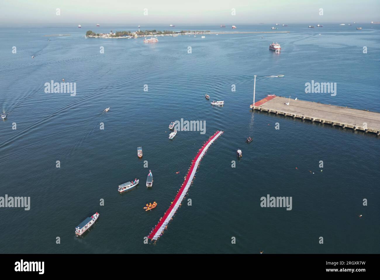 Makassar, Sulawesi meridionale, Indonesia. 12 agosto 2023. Foto aerea di un certo numero di nuotatori che sventolano e sfilano la bandiera della Repubblica di Indonesia nello stretto di Makassar, Sulawesi meridionale Indonesia, sabato 12 agosto 2023. Allo scoppio della bandiera della Repubblica di Indonesia, alta 78 metri, hanno partecipato 140 nuotatori e hanno sfilato per 1,8 chilometri nuotando. (Immagine di credito: © Moh Niaz Sharief/ZUMA Press Wire) SOLO USO EDITORIALE! Non per USO commerciale! Foto Stock