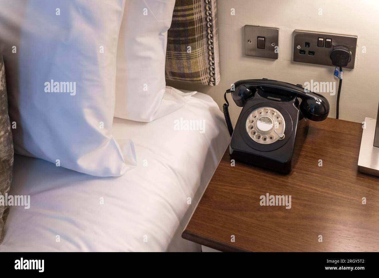 Telefono vecchio stile per il servizio in camera su un comodino della camera da letto dell'hotel Foto Stock