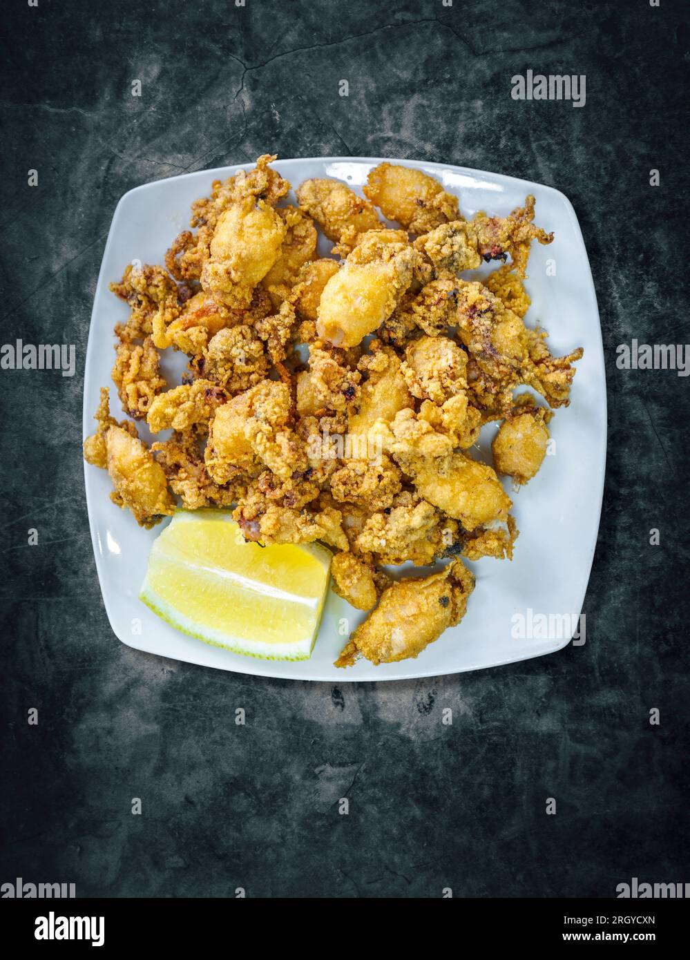Calamari fritti (chiama Chopitos in spagnolo) in stile andaluso su un tavolo in marmo nero. Foto Stock