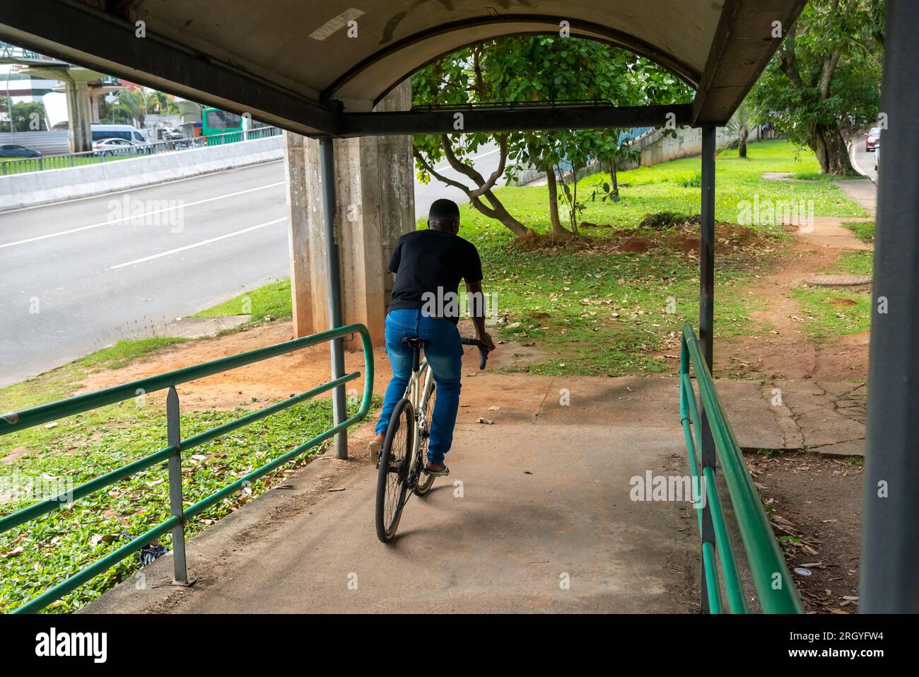 Salvador, Bahia, Brasile - 11 agosto 2023: Un ciclista che attraversa la passerella pedonale con la sua bicicletta sull'Avenida Tancredo Neves a Salvador, Bahia, Foto Stock