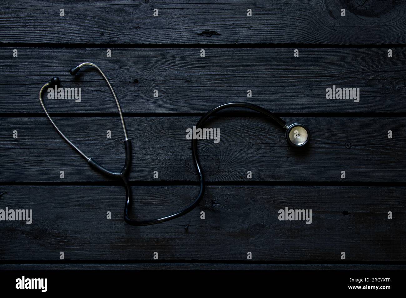 Stetoscopio si trova su una tavola di legno nero da vicino, salute e medicina Foto Stock