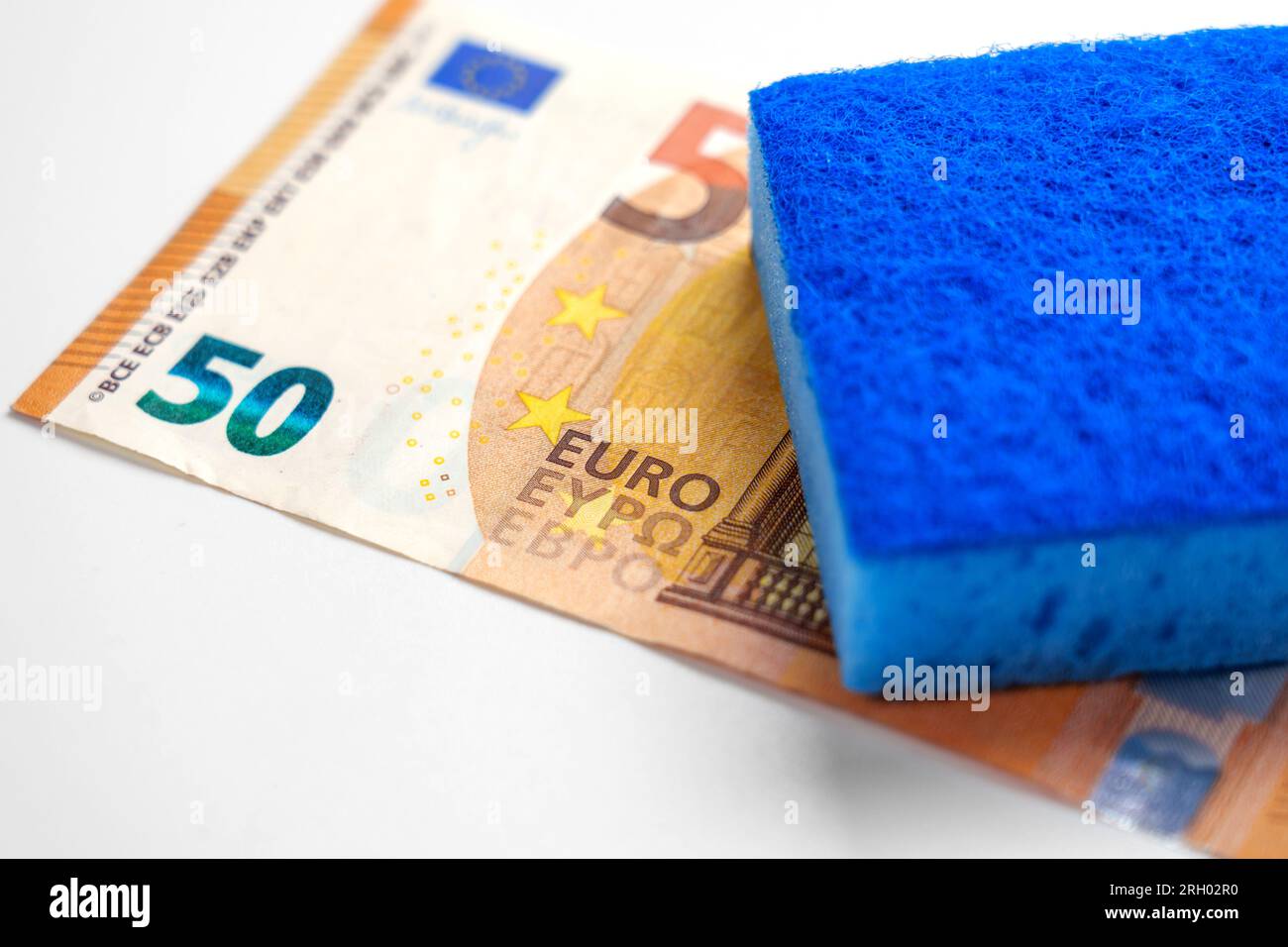 Concetto di riciclaggio di denaro. Pulizia criminale delle banconote in euro. Moneta europea in contanti con spugna blu Foto Stock