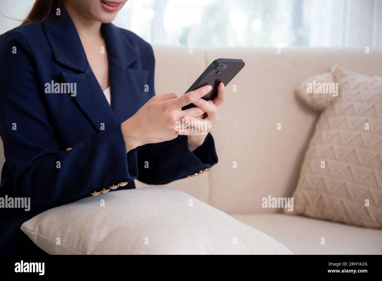 Primo piano le mani di una donna d'affari asiatica che usa lo smartphone ai social media online seduto sul divano in salotto a casa, donna d'affari che sembra un phon intelligente Foto Stock